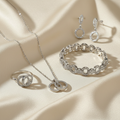 Luxury Italian-inspired white gold jewelry set with interlocking pattern on cream silk